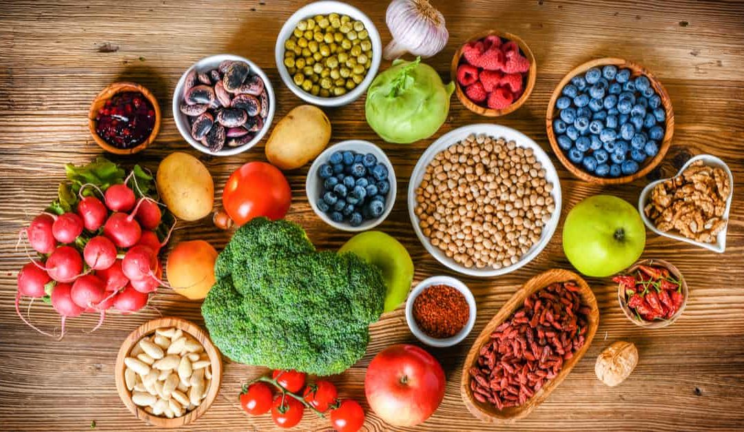 a variety of superfoods: vegetables, fruits, berries , seeds, cereal laid out on a wooden table