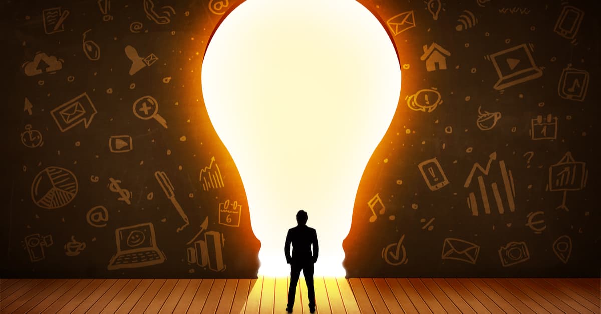 Man standing in front of a large light bulb, being illuminated with ideas.